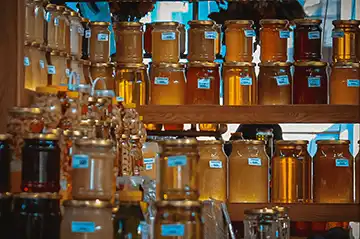 Shelves of golden honey in labelled jars.